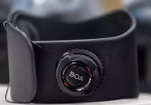 Close-up of the BOA micro-adjustable dial and aircraft-grade stainless steel laces on a wrist-to-elbow brace, showing how the tension system provides a custom, secure fit